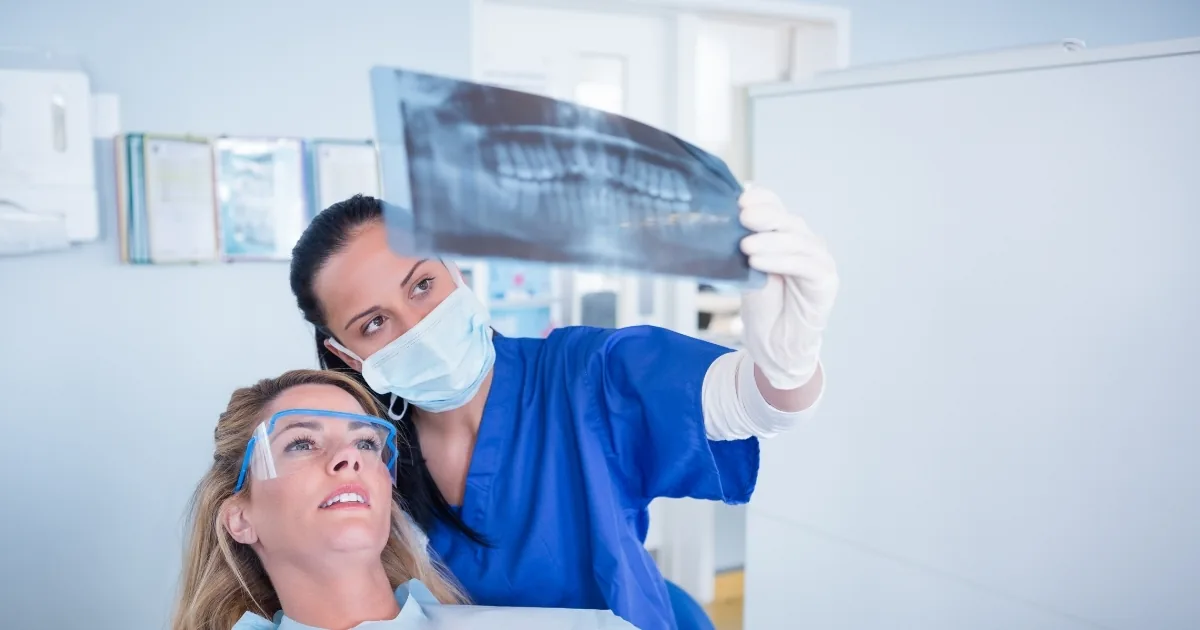 Dentist showing a dental X-ray to a patient during a consultation, discussing a treatment plan before crowns or veneers