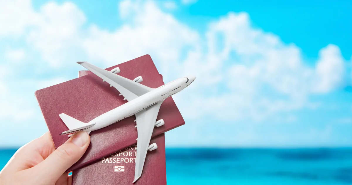 Hand holding a model aeroplane over two passports against a blue sky — visa and entry planning for medical treatment in Turkey